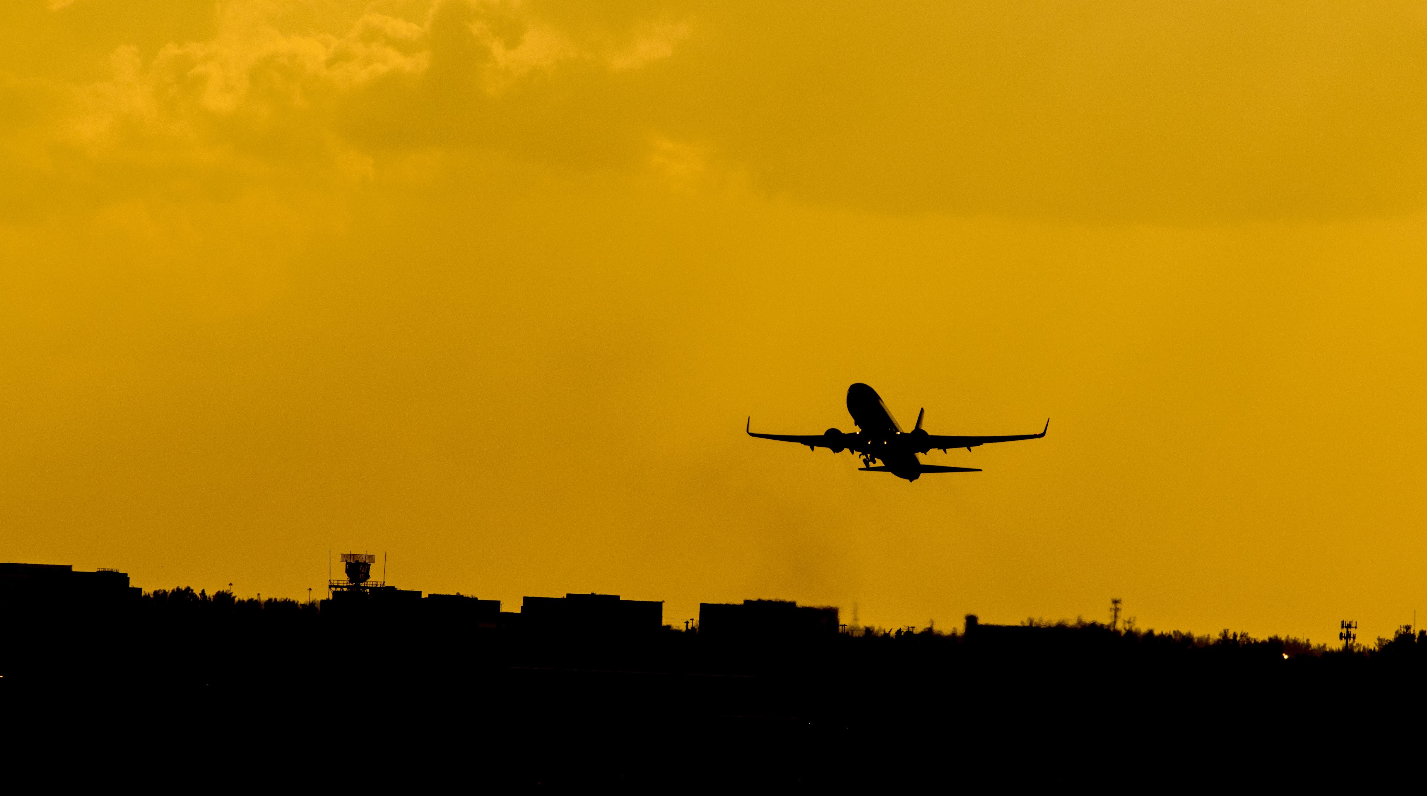 A silhouette of an airplane, taking off into the sunset