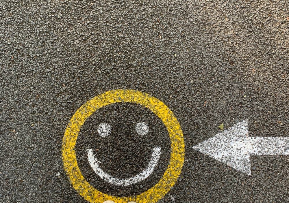 A smiley face with an arrow pointing at it, painted on pavement